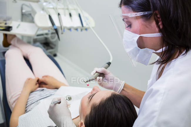 Odontoiatra che esamina una paziente con strumenti presso una clinica dentistica — Foto stock