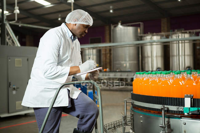 Чоловік-працівник перевіряє пляшки на заводі соків — стокове фото