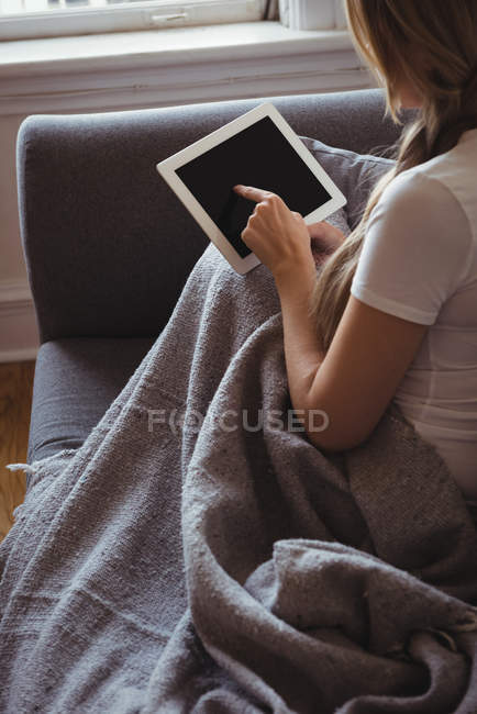 Frau nutzt digitales Tablet auf Sofa im Wohnzimmer — Stockfoto