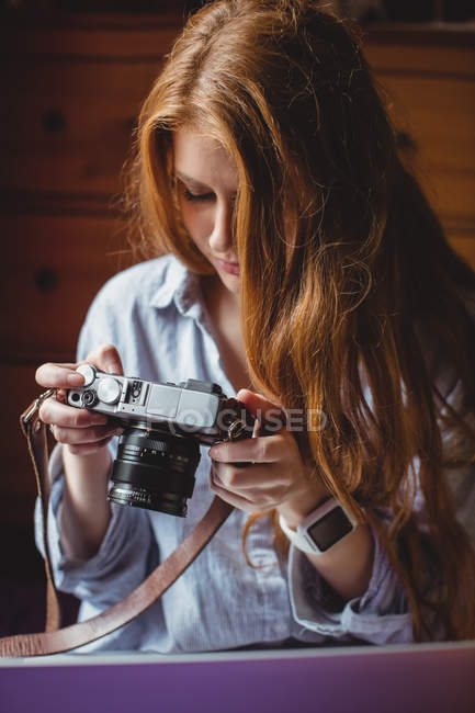 Mulher bonita olhando para fotos na câmera digital em casa — Fotografia de Stock