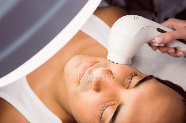 Médico realizando depilación láser en la cara del paciente en la clínica - foto de stock