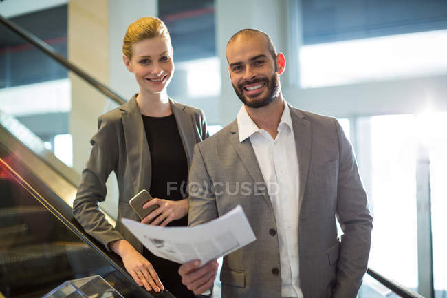 Business people standing on escalator with luggage at airport — Stock Photo