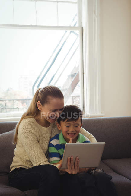 Mère et fils utilisant une tablette numérique dans le salon à la maison — Photo de stock