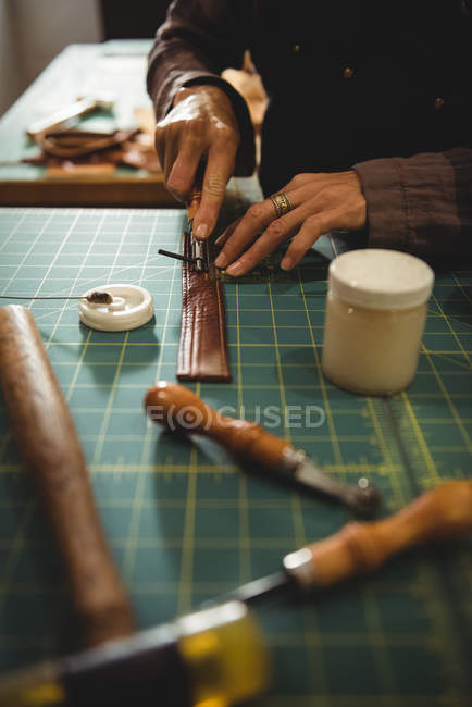Mid-section of craftswoman cutting leather in workshop — Stock Photo