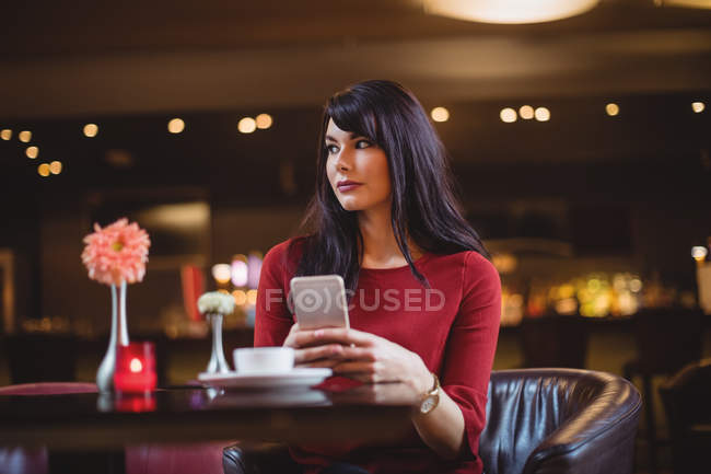 Woman holding mobile phone in restaurant — Stock Photo