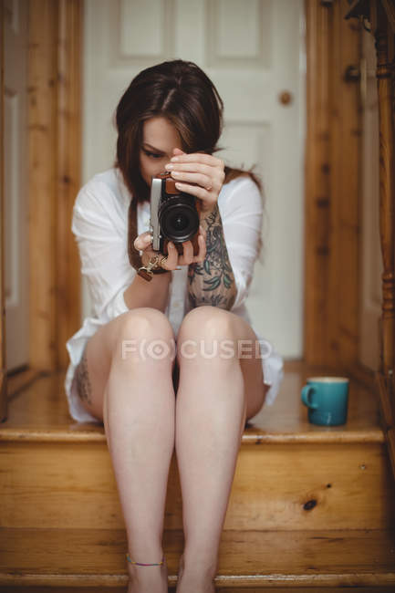 Mujer tomando fotos en cámara digital en casa - foto de stock