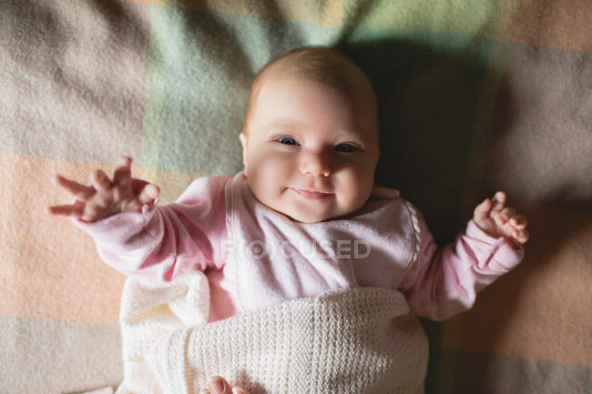 Nahaufnahme des süßen lächelnden Babys, das zu Hause im Schlafzimmer auf dem Bett liegt — Stockfoto