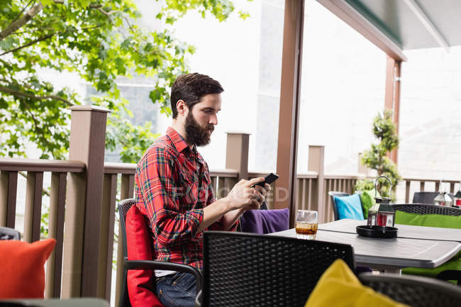 Homem usando telefone celular enquanto sentado no bar — Fotografia de Stock