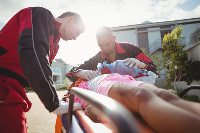 Paramedic giving oxygen to injured girl at accident spot — Stock Photo