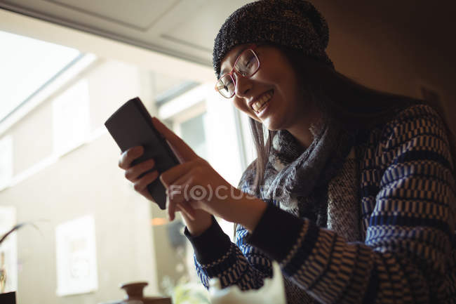 Lächelnde Frau benutzt Handy am Fenster eines Cafés — Stockfoto
