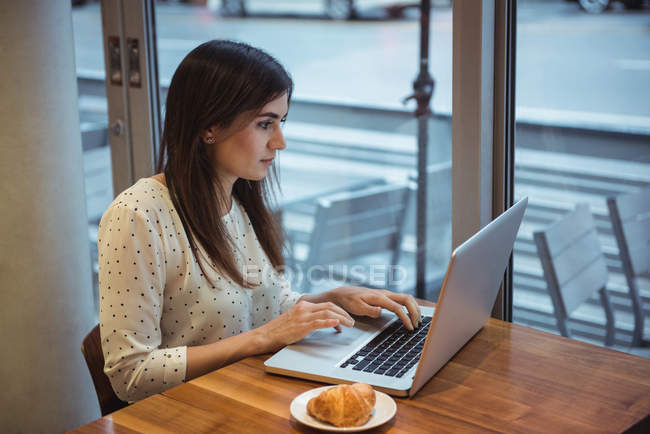 Beautiful businesswoman using laptop at cafe table — Stock Photo