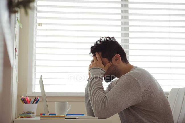 Gestresster Mann sitzt zu Hause mit den Händen auf dem Kopf — Stockfoto