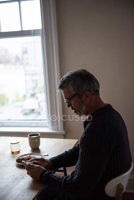 Человек, использующий мобильный телефон в гостиной у себя дома — стоковое фото