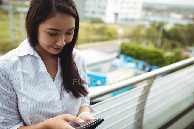 Young businesswoman using mobile phone at office balcony — Stock Photo