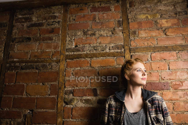 Belle femme debout contre un mur de briques — Photo de stock