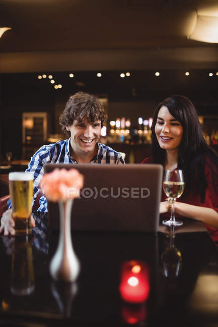 Casal usando laptop enquanto bebe no bar — Fotografia de Stock