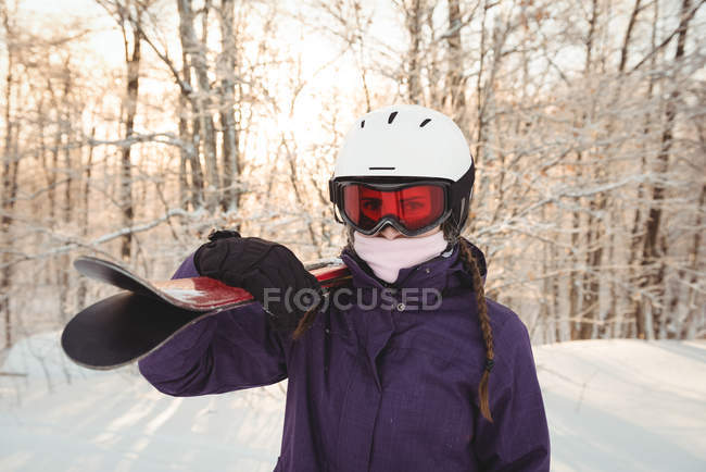 Portrait of woman in ski wear holding skis on her shoulder — Stock Photo