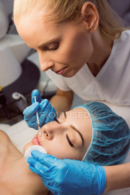 Close-up de médico fêmea fazendo injeção facial para mulher jovem na clínica — Fotografia de Stock