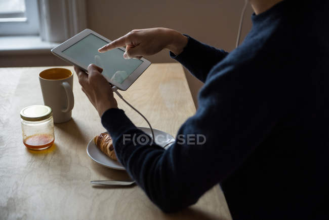 Mid-section of man listening music on digital tablet at home — Stock Photo