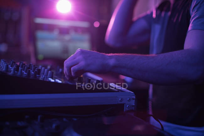 Seção intermediária do dj masculino misturando música no console de mistura no bar — Fotografia de Stock