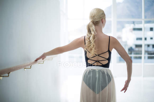 Ballerina che si estende su una sbarra mentre pratica la danza classica in studio — Foto stock