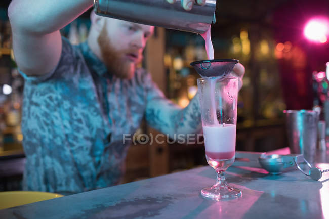 Cantinero preparando un cóctel en el mostrador en el bar - foto de stock
