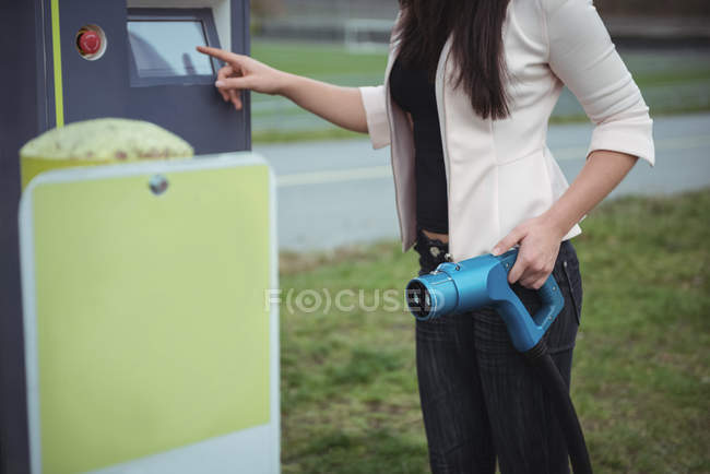 Sezione centrale della donna che utilizza la macchina elettrica plug-in sulla strada — Foto stock