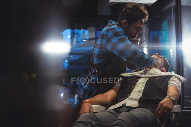 Homme barbier rasage client barbe dans le salon de coiffure — Photo de stock