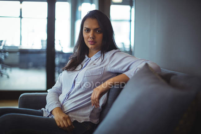 Portrait of businesswoman sitting on sofa in office — Stock Photo