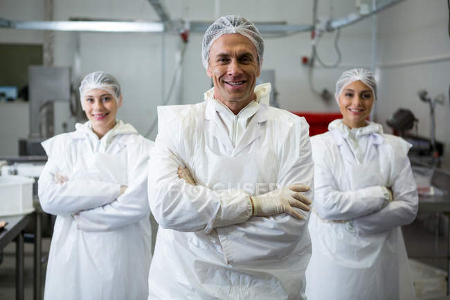 Macellai in piedi con le braccia incrociate in fabbrica di carne — Foto stock