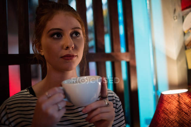 Thoughtful woman holding coffee cup in the bar — Stock Photo