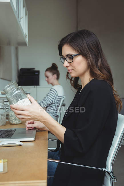 Business Executive regardant pot de cailloux dans le bureau — Photo de stock