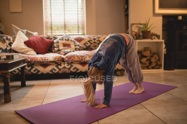 Chica realizando yoga en la sala de estar en casa - foto de stock