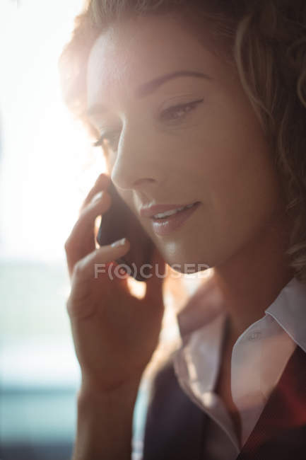 Businesswoman talking on mobile phone in office — Stock Photo