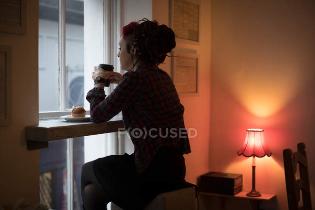 Задумчивая женщина за чашкой кофе в интерьере кафе — стоковое фото