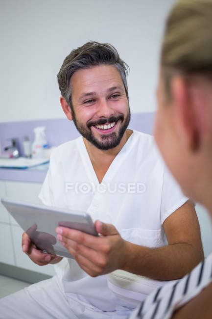 Доктор тримає цифровий планшет під час розмови з пацієнтом у клініці — стокове фото