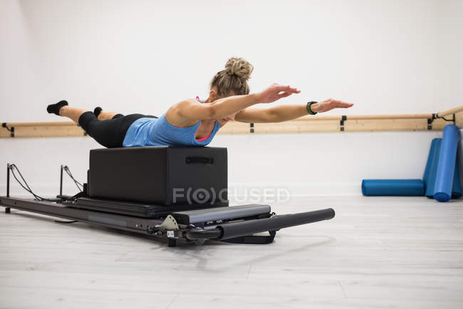 Femme blonde exerçant sur le réformateur dans la salle de gym — Photo de stock
