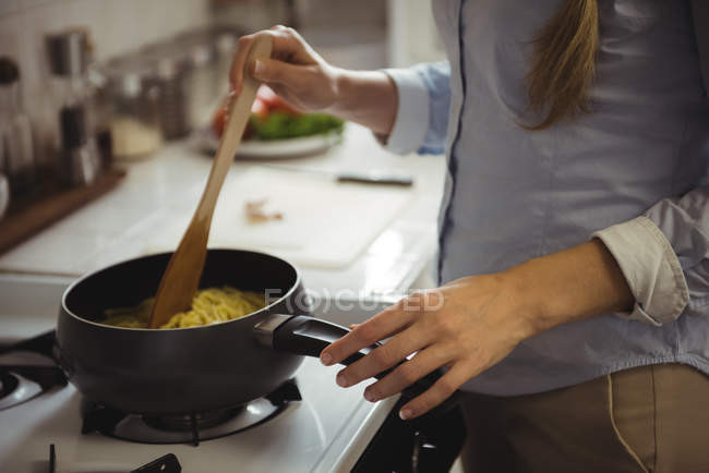Mid section of woman preparing noodles in kitchen at home — Stock Photo