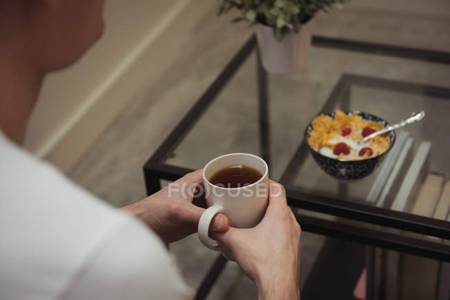Close-up of man having cup of coffee and cereals — Stock Photo