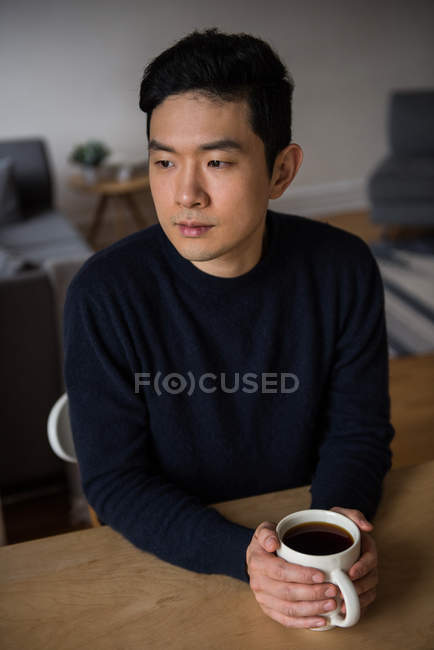 Homme réfléchi tenant une tasse de café noir à la maison — Photo de stock