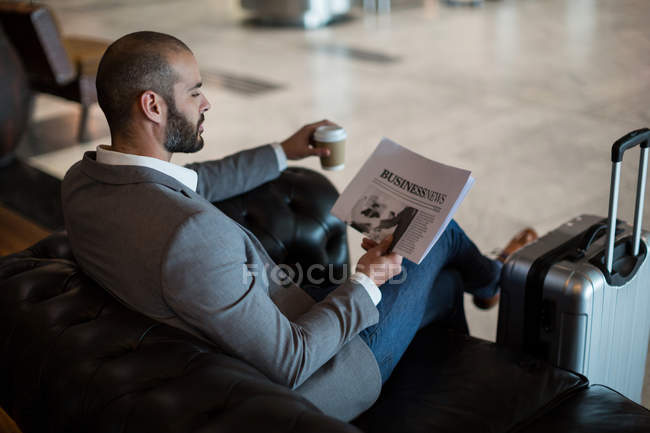 Geschäftsmann liest Zeitung im Wartebereich am Flughafen-Terminal — Stockfoto