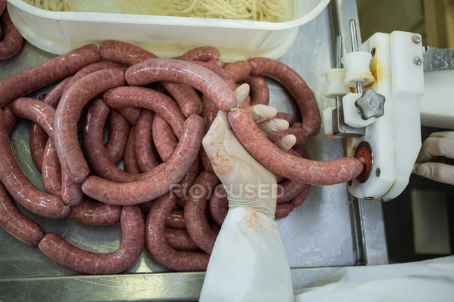 Close-up of butcher processing sausages in meat factory — Stock Photo
