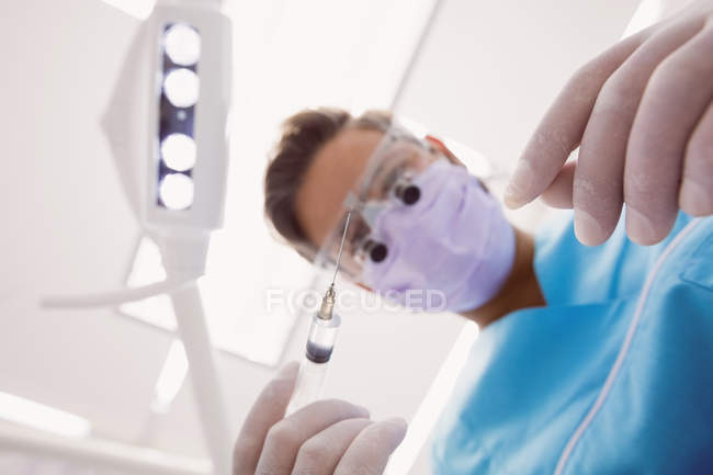 Visão de baixo ângulo do dentista segurando ferramentas odontológicas na clínica odontológica — Fotografia de Stock