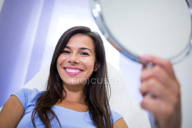 Retrato de paciente sorrindo segurando espelho na clínica — Fotografia de Stock