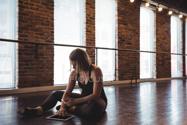 Танцівниця використовує мобільний телефон та цифровий планшет у танцювальній студії — стокове фото