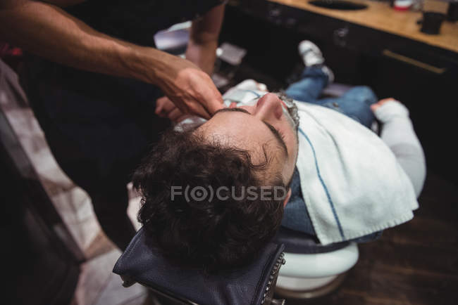 Client getting beard shaved in barber shop — Stock Photo