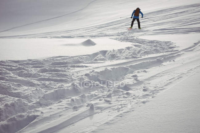Vista lateral do esqui esquiador em montanhas cobertas de neve — Fotografia de Stock