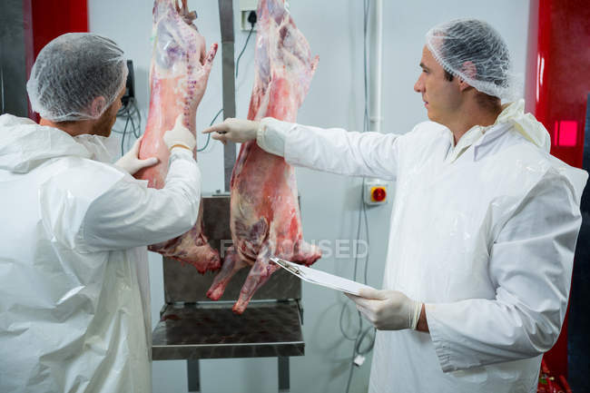 Carniceros que interactúan entre sí en la fábrica de carne - foto de stock