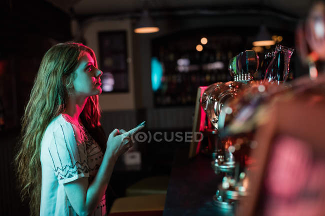 Schöne Frau benutzt Handy am Tresen in Bar — Stockfoto