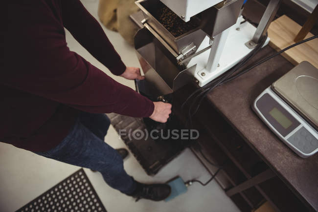 Homem segurando saco de plástico na frente da máquina de pesagem no café — Fotografia de Stock